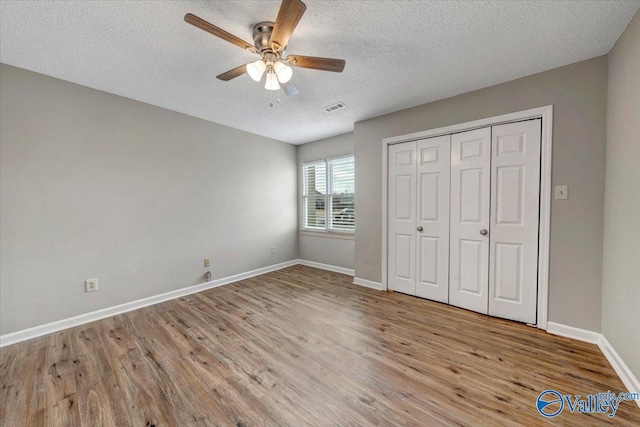 unfurnished bedroom with a textured ceiling, light wood-type flooring, a closet, and ceiling fan