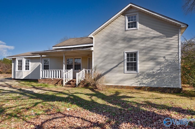 rear view of house featuring a yard and a porch