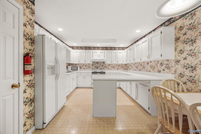 kitchen with a kitchen island, a textured ceiling, white appliances, and white cabinetry