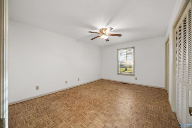 unfurnished bedroom with ceiling fan, two closets, and parquet floors