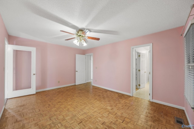 empty room featuring ceiling fan, a textured ceiling, and light parquet floors