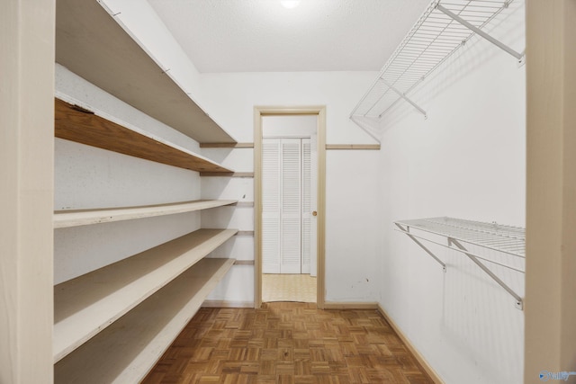 spacious closet featuring dark parquet floors