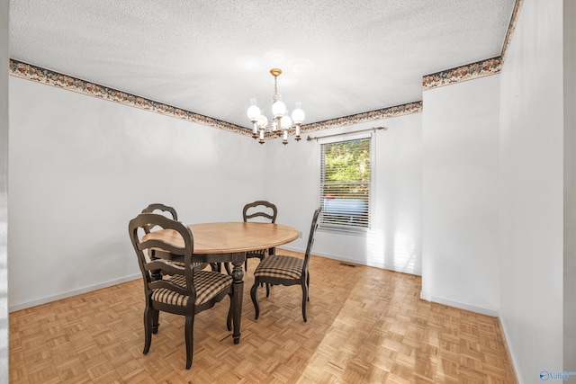 dining room featuring an inviting chandelier, light parquet floors, and a textured ceiling