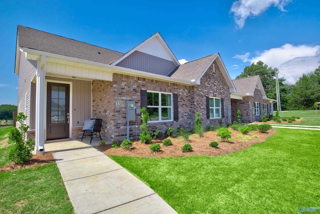 view of front of house featuring a shingled roof, brick siding, and a front lawn