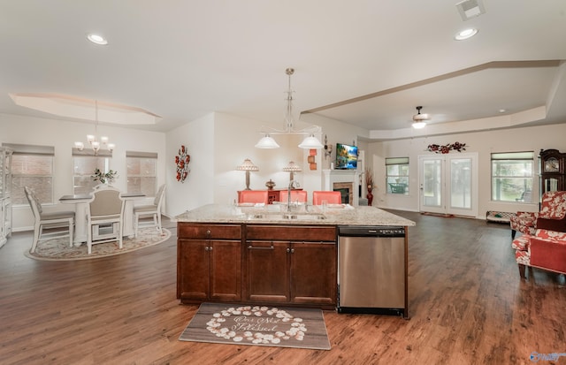 kitchen featuring ceiling fan with notable chandelier, dishwasher, hardwood / wood-style flooring, a tray ceiling, and sink