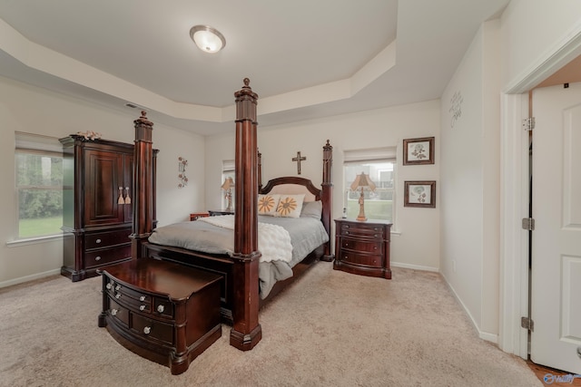 carpeted bedroom featuring a raised ceiling and multiple windows