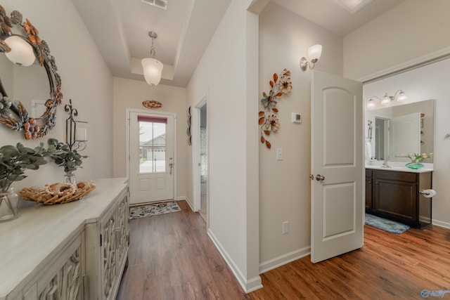 corridor featuring sink, hardwood / wood-style flooring, and a raised ceiling