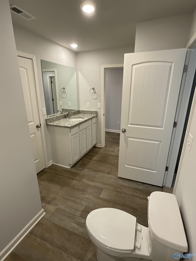 bathroom featuring hardwood / wood-style flooring, toilet, and vanity