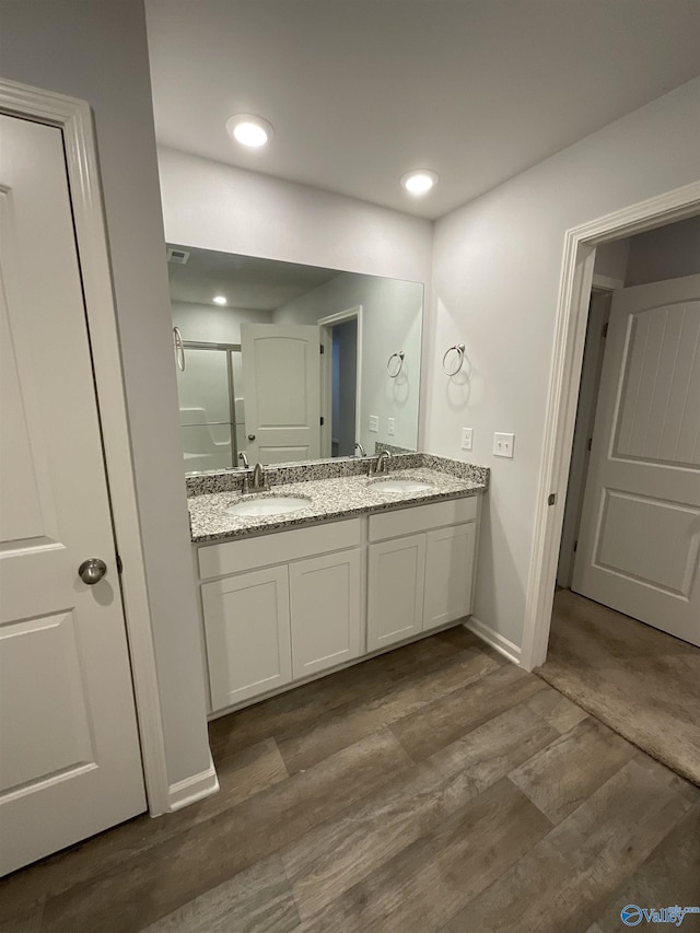 bathroom with vanity, wood-type flooring, and a shower with door