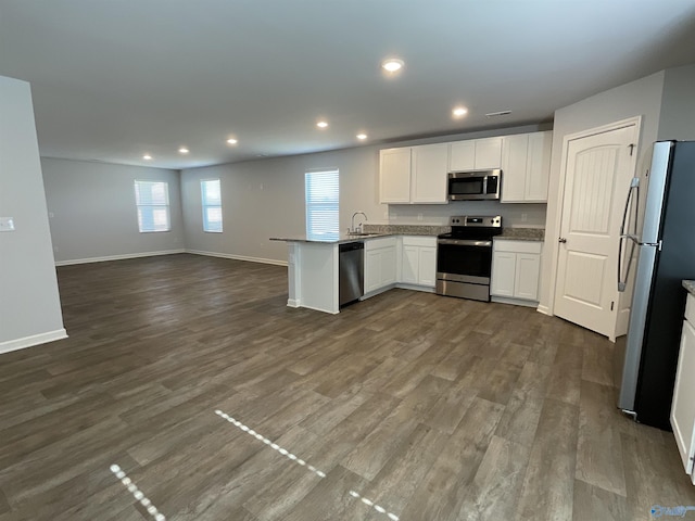 kitchen featuring kitchen peninsula, sink, stainless steel appliances, white cabinets, and dark hardwood / wood-style flooring