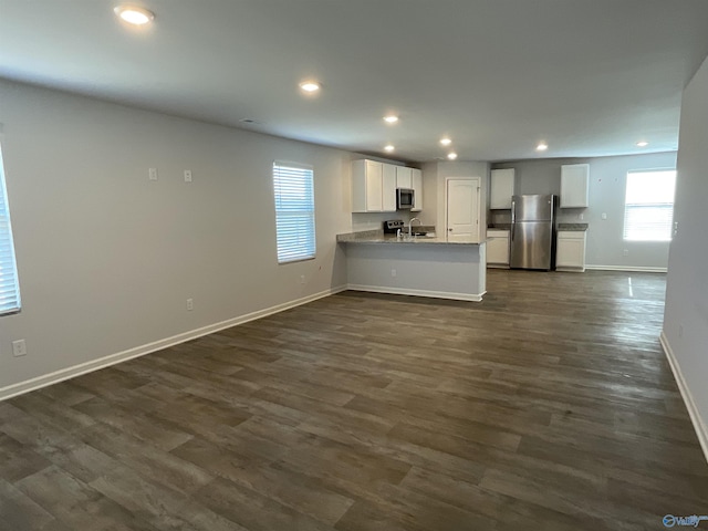 kitchen with dark hardwood / wood-style floors, white cabinetry, appliances with stainless steel finishes, and kitchen peninsula