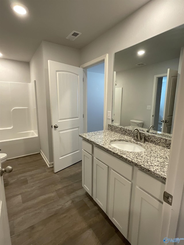 full bathroom with washtub / shower combination, hardwood / wood-style floors, toilet, and vanity