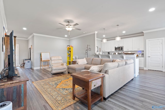 living room featuring hardwood / wood-style floors, ceiling fan, and ornamental molding