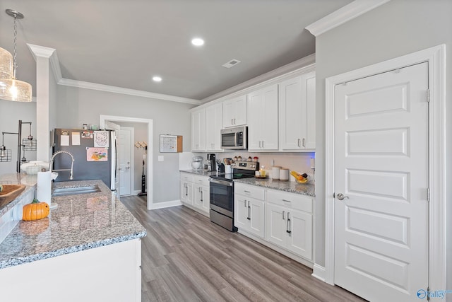 kitchen featuring white cabinets, light wood-type flooring, decorative light fixtures, and appliances with stainless steel finishes