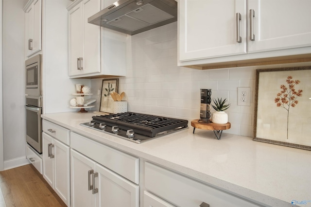 106 Kite Cir, Madison, AL 35756 - kitchen with exhaust hood, appliances with stainless steel finishes, white cabinets, tasteful backsplash, and wood finished floors
