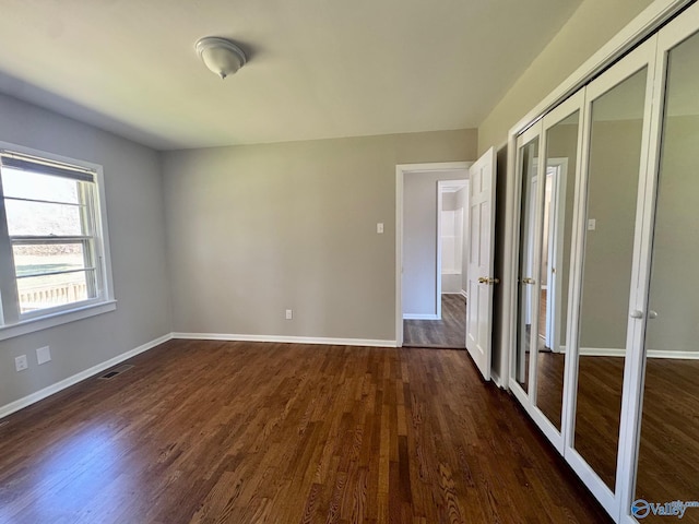 empty room with baseboards, visible vents, and dark wood-type flooring