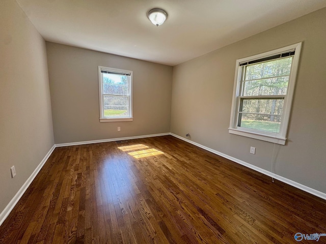 unfurnished room with dark wood-type flooring and baseboards