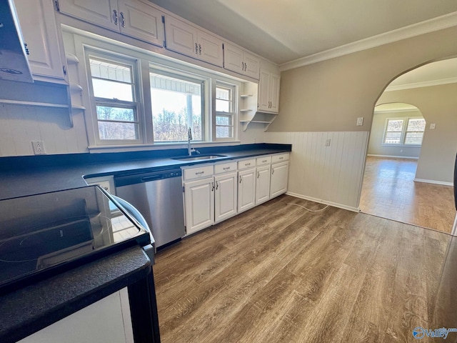 kitchen featuring open shelves, dark countertops, stainless steel dishwasher, a sink, and wood finished floors