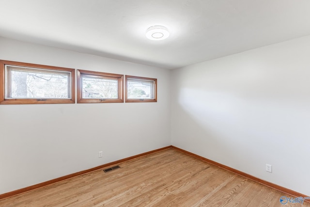 spare room with baseboards, visible vents, and light wood finished floors