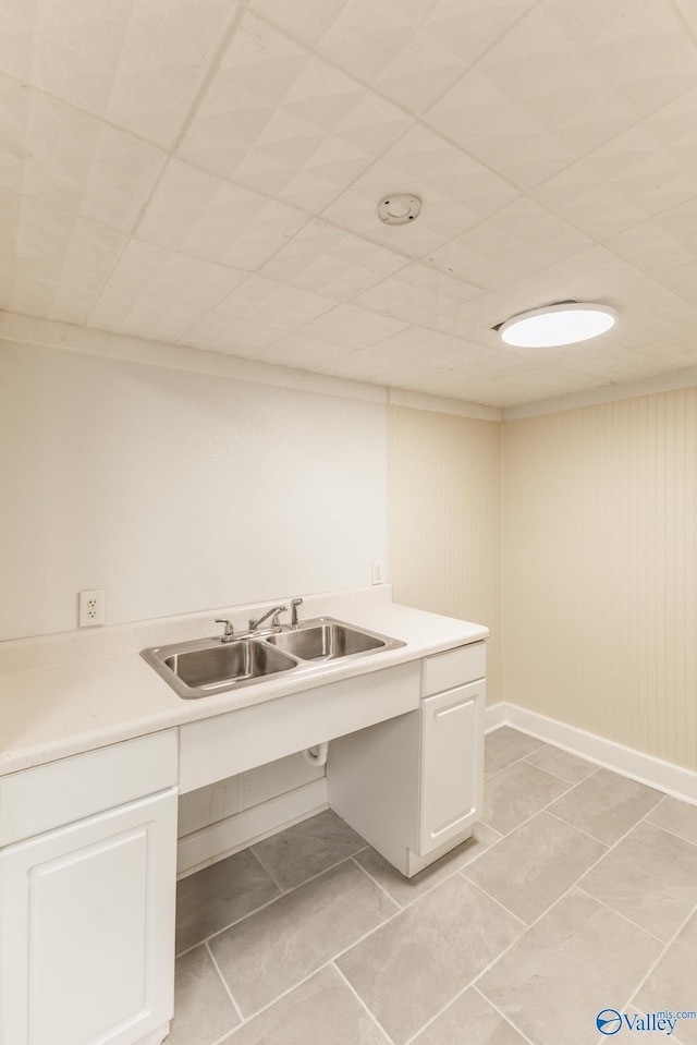 kitchen featuring light countertops, white cabinets, light tile patterned floors, and a sink