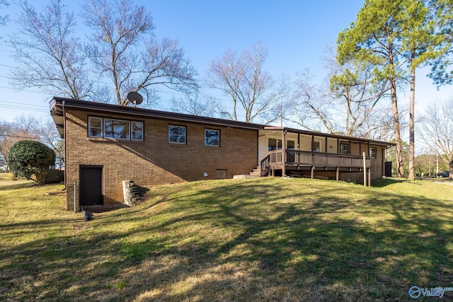 back of property featuring brick siding, a deck, and a yard