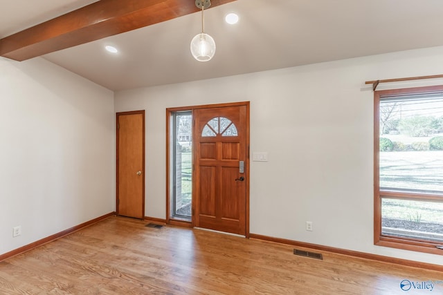 foyer entrance featuring visible vents, baseboards, light wood-style floors, and beamed ceiling