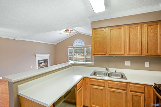 kitchen with sink, ceiling fan, a fireplace, a textured ceiling, and kitchen peninsula