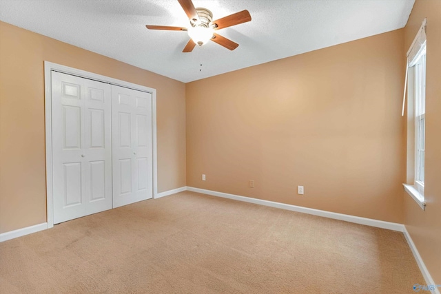 unfurnished bedroom with ceiling fan, carpet flooring, a textured ceiling, and a closet