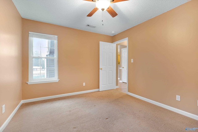 empty room with light carpet, ceiling fan, and a textured ceiling