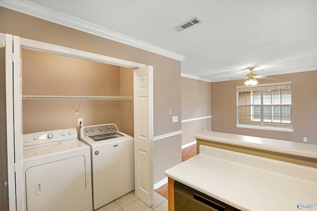 laundry area with ceiling fan, ornamental molding, a textured ceiling, washing machine and clothes dryer, and light tile patterned flooring