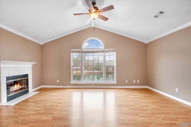 unfurnished living room featuring lofted ceiling, a textured ceiling, a tile fireplace, and light wood-type flooring