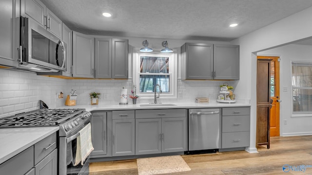111 Althea St, Gadsden, AL 35904 - kitchen with appliances with stainless steel finishes, a sink, gray cabinets, a textured ceiling, and light wood-type flooring