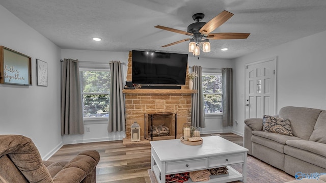 111 Althea St, Gadsden, AL 35904 - living room with a fireplace, a textured ceiling, light wood finished floors, ceiling fan, and baseboards