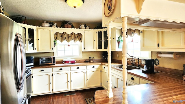 kitchen with a textured ceiling, sink, stainless steel appliances, and dark wood-type flooring