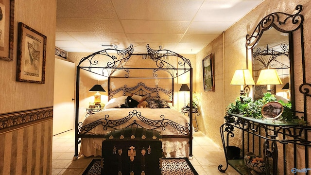 bedroom featuring a drop ceiling and light tile patterned floors