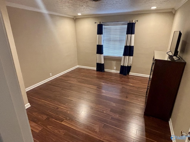 spare room with a textured ceiling, ornamental molding, and dark wood-type flooring