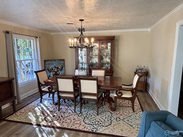 dining area with ornamental molding, wood-type flooring, a textured ceiling, and an inviting chandelier