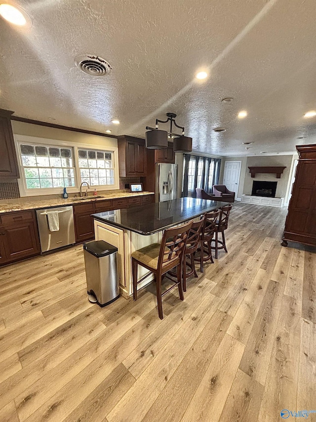 kitchen featuring a breakfast bar, a textured ceiling, stainless steel appliances, sink, and light hardwood / wood-style floors