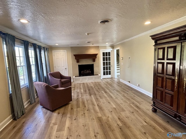 living room with a textured ceiling, light wood-type flooring, and ornamental molding