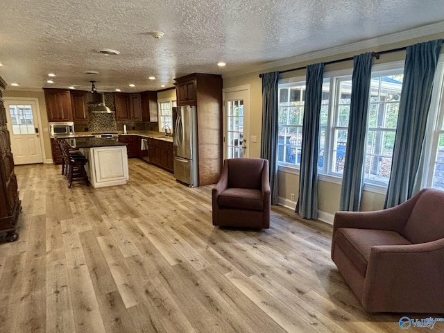 living room featuring a textured ceiling, light wood-type flooring, and crown molding