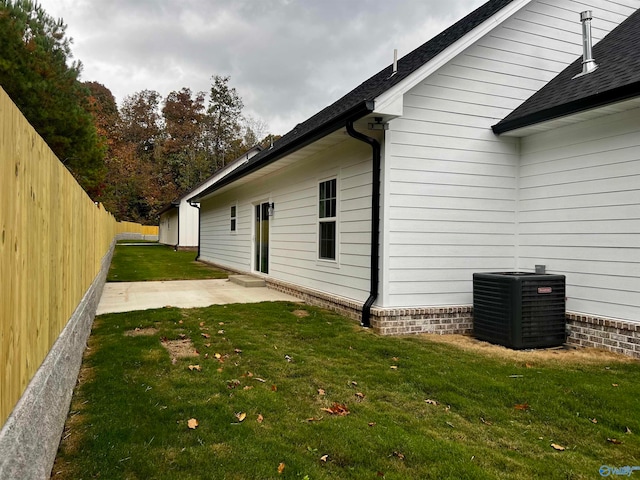 view of side of property featuring a patio, central AC, and a lawn