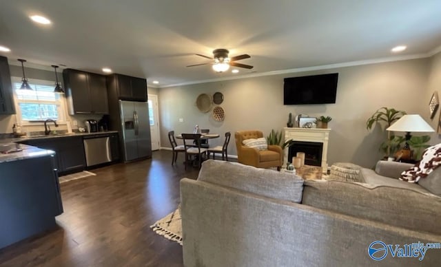 living room featuring a ceiling fan, dark wood-style floors, ornamental molding, a fireplace, and recessed lighting