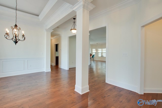 unfurnished dining area featuring wood finished floors, decorative columns, and crown molding