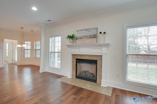 unfurnished living room with baseboards, visible vents, ornamental molding, wood finished floors, and a fireplace