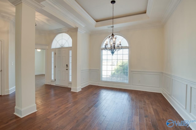 entryway with a raised ceiling, decorative columns, and an inviting chandelier