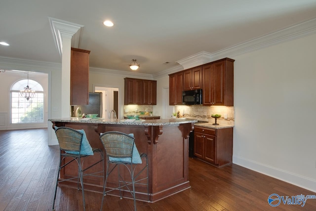 kitchen with light stone counters, black microwave, dark wood-type flooring, and backsplash