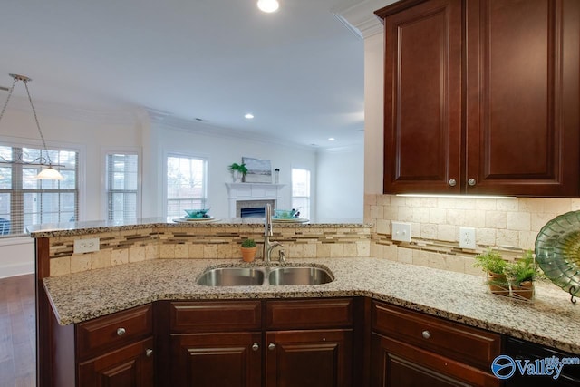 kitchen with a peninsula, crown molding, decorative backsplash, and a sink