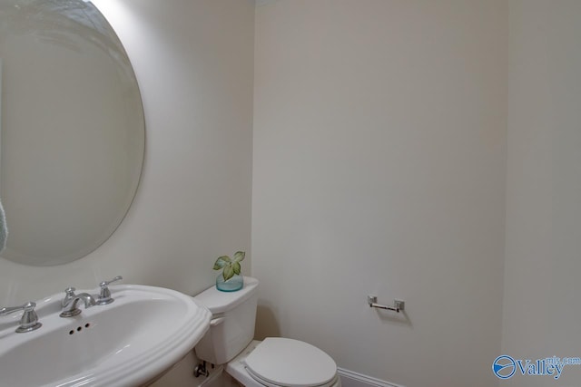 bathroom with toilet, baseboards, and a sink