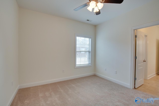 spare room featuring a ceiling fan, visible vents, light carpet, and baseboards