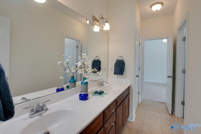 bathroom featuring baseboards, double vanity, a sink, and tile patterned floors